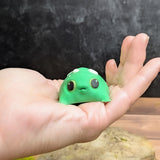 Blob frog sitting in the center of an open palm, emphasizing its small, plump size and slightly startled expression.