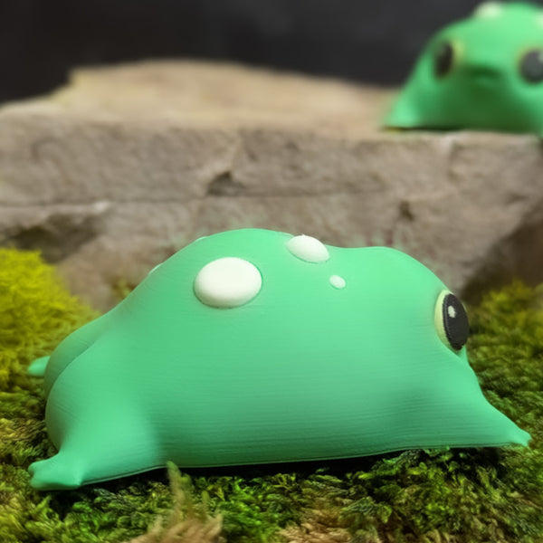 Side view of the blob frog with a second identical frog in the background, creating depth and showing multiple angles.