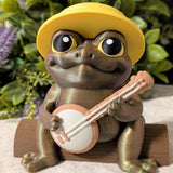 Close-up of a frog figurine with oversized eyes, yellow sun hat, and a banjo resting in its hands.