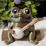 Frog figurine with a banjo and yellow hat sitting on a surface, surrounded by purple flowers, without a hat