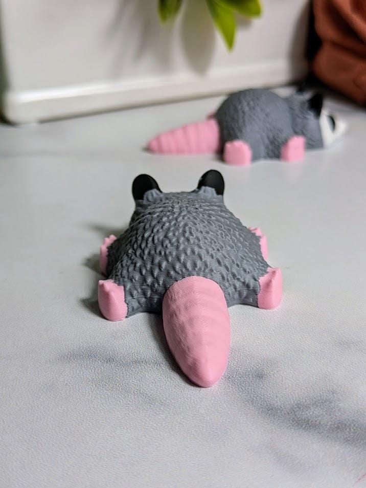 Back of the Blob Possum figurine showing its smooth, rounded shape and pink tail.