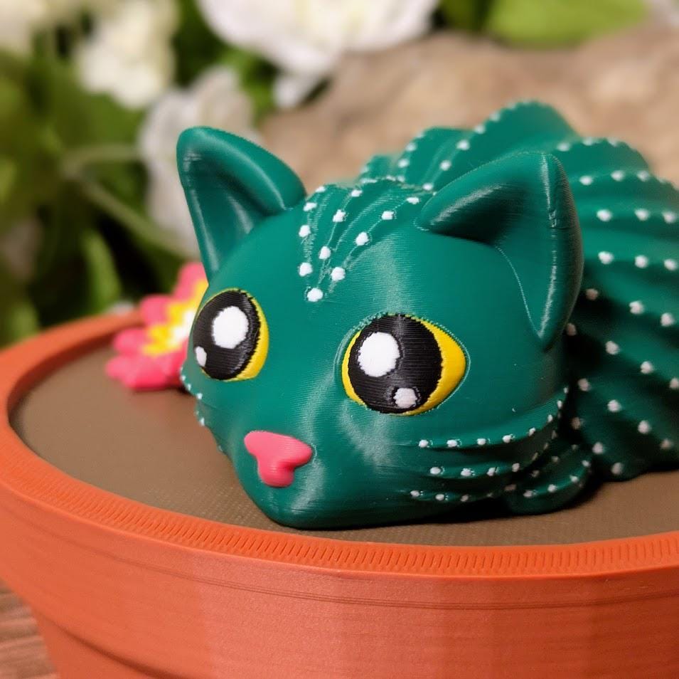 Front view of cactus cat figurine with wide eyes and pink flower in terracotta pot.