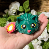 Cactus cat figurine with flower held in hand, showing small desk-friendly size.