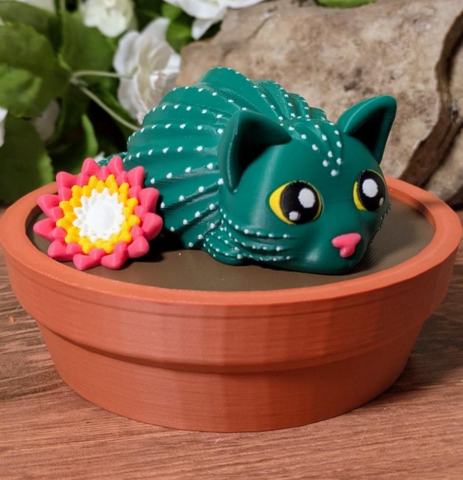 Cactus cat figurine with flower, sitting in pot with floral background.