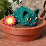 Cactus cat figurine with flower, sitting in pot with floral background.