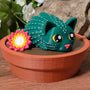 Cactus cat figurine with flower, sitting in pot with floral background.