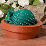 Side view of cactus cat curled in terracotta dish, textured like a cactus with dotted ridges.