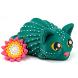An adorably cute cat that is also a cactus sits on a white background. The cat has a pink nose, yellow eyes, and a flower on its tail that is pink, yellow and white.