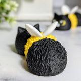 Back view of the Cat Bee figurine, showing its fuzzy black texture, yellow stripe, and small white wings.