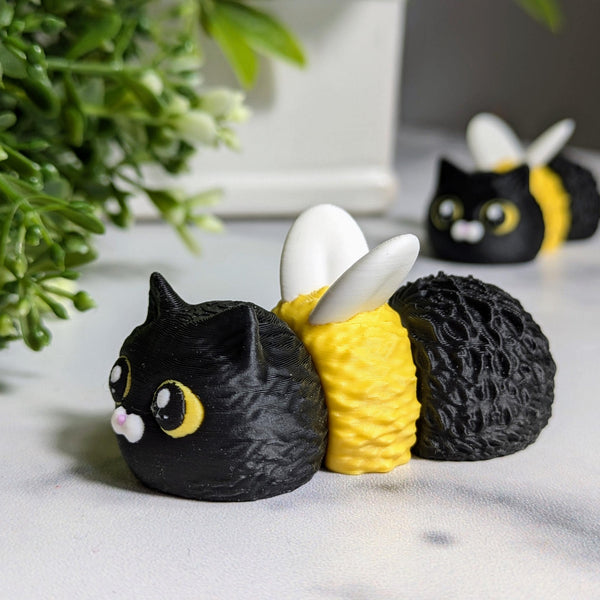 Cat Bee faces forward in a leafy setup, flaunting its round yellow body, perky ears, and bee wings.