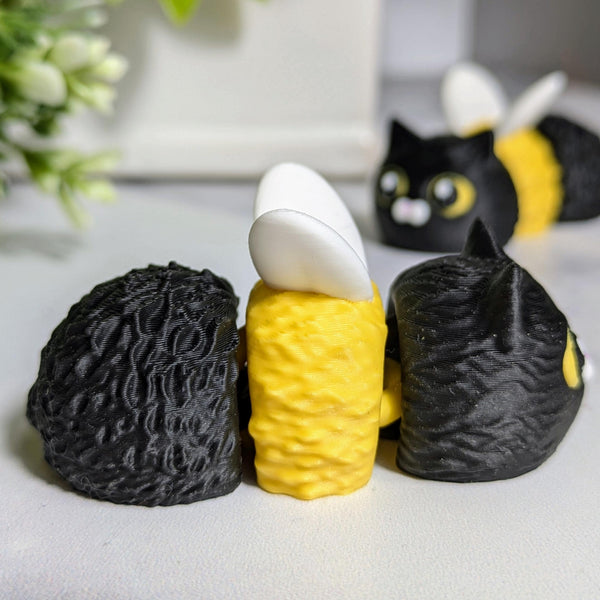 Side view of the cat bee, lying on a white surface with another cat bee in the background.