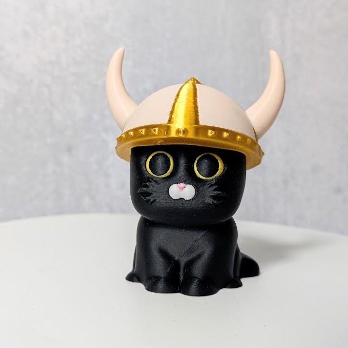Black cat figurine with a horned golden viking helmet.