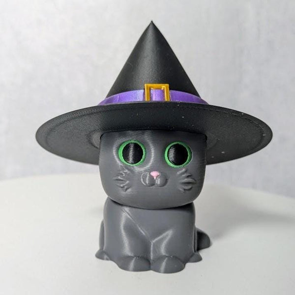 Gray cat figurine with a tall black witch hat, complete with a sparkling purple band.