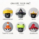 Illustrated display of six interchangeable hats for cat figurines, including cheese, traffic cone, frog, witch, mushroom, and viking styles.