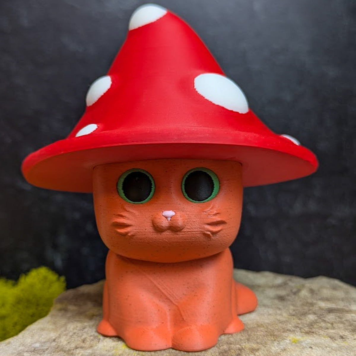 An orange cat figurine with a tall red toadstool-style hat featuring large white spots.