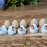 A lineup of miniature chicken and egg figurines arranged in alternating order on a wooden surface.
