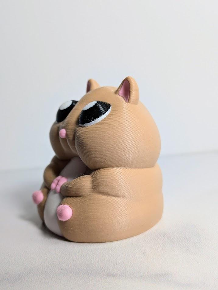 Three-quarter angle of a chubby hamster figurine, showing its little pink feet and big glossy eyes.