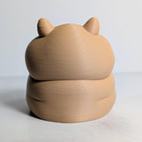 Rear view of a plump hamster figurine with small ears and a rounded back.