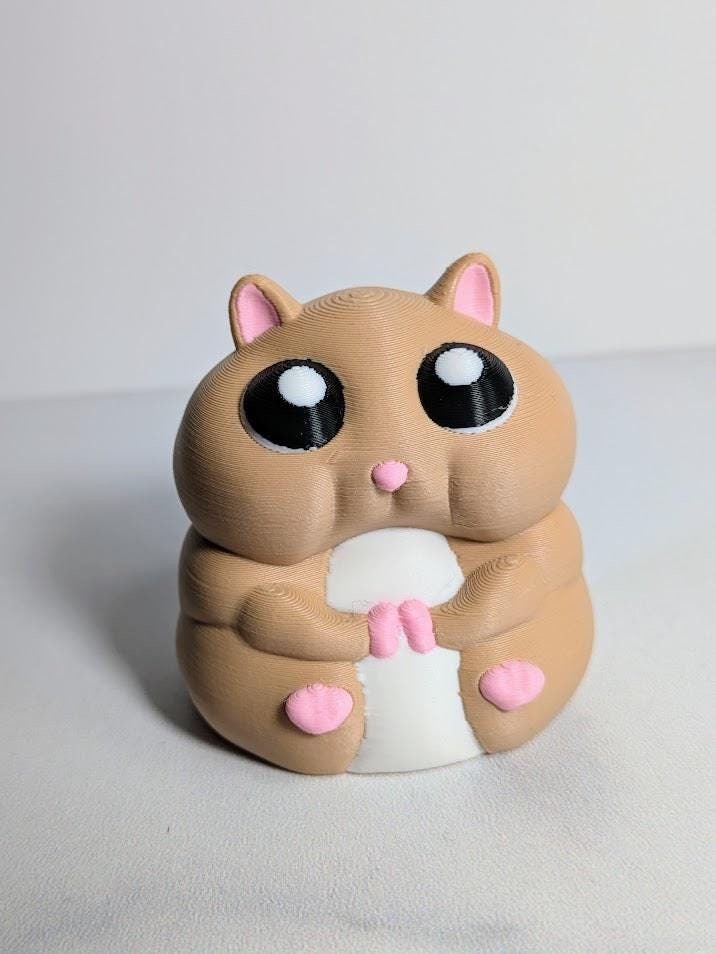 Close-up front view of a hamster figurine with giant eyes and tiny paws.