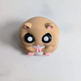 Front view of a round hamster figurine with big eyes and tiny pink feet