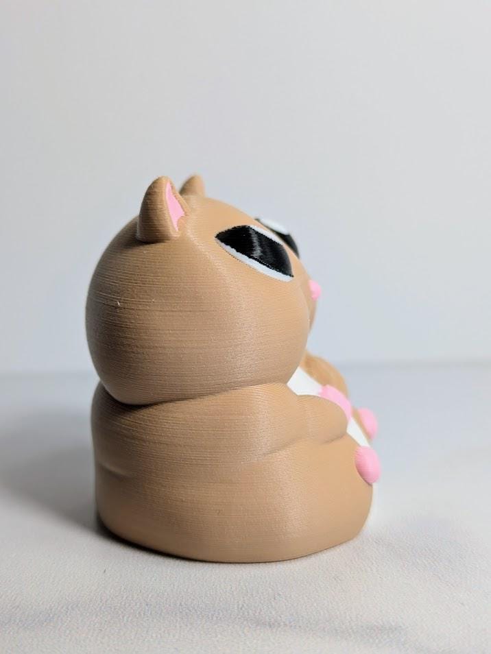 Side profile of a chunky hamster figurine showing its soft curves and tiny hands