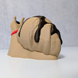 Angled view of Le Escargôutier™, showing off the chocolate-drizzled swirl of his croissant shell as he plots his next pastry heist.