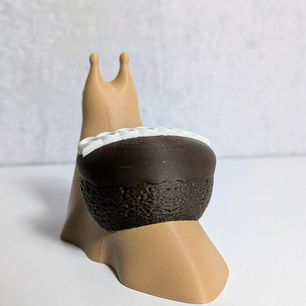 Rear view of a cupcake snail showing off its chocolate cupcake shell with white frosting peeking over the edge.