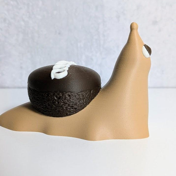 Side view of a cupcake snail figurine with a tan body and a chocolate cupcake for a shell, topped with white frosting