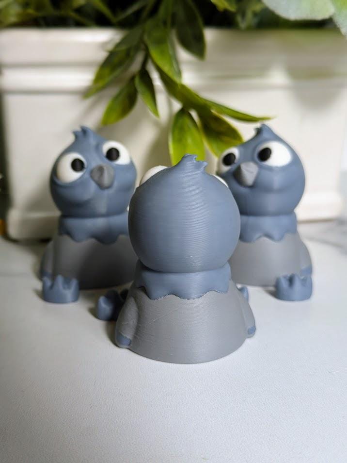 Rear view of a derpy pigeon figurine showing off their rounded back and tiny tail beneath hanging greenery.
