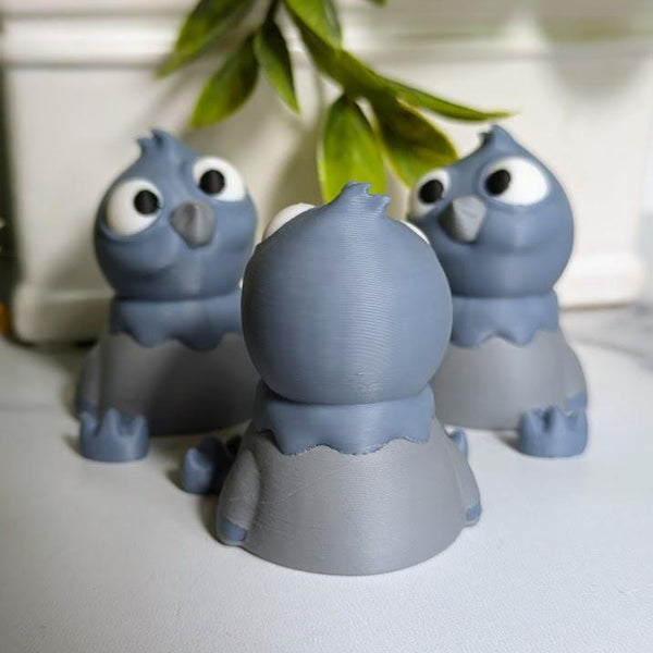 Rear view of a derpy pigeon figurine showing off their rounded back and tiny tail beneath hanging greenery.