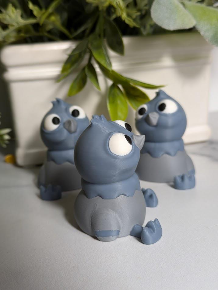 Three wide-eyed derpy pigeon figurines stand in a row under a leafy plant, each looking in slightly different, equally confused directions.
