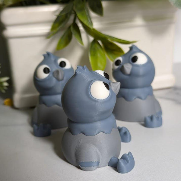 Three wide-eyed derpy pigeon figurines stand in a row under a leafy plant, each looking in slightly different, equally confused directions.