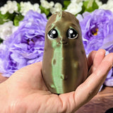 Emotional Support Pickle held in a hand for size reference, with a purple floral background.