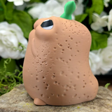 Side profile of the potato showing textured skin, tiny arm, and one wide eye peeking upward.