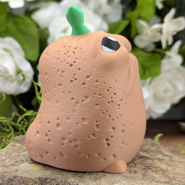 Side angle of the potato looking up and to the left, showing a single eye and its round stubby feet.