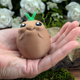 The smaller potato figure nestled gently in a hand, emphasizing its petite and squeezable size.