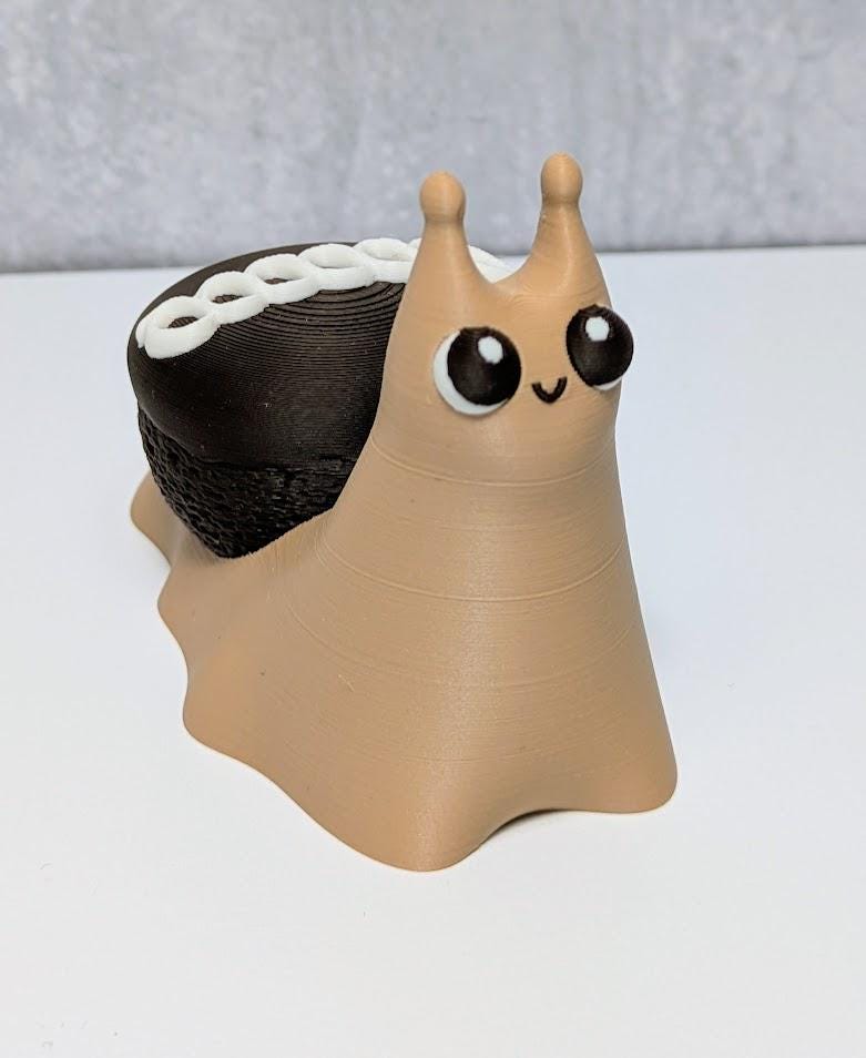 Front view of a cupcake snail with expressive eyes and a chocolate swirl shell, resembling a Hostess snack.