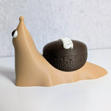 Side view of a cupcake snail figurine with a chocolate shell decorated like a Hostess cupcake, complete with frosting squiggle.
