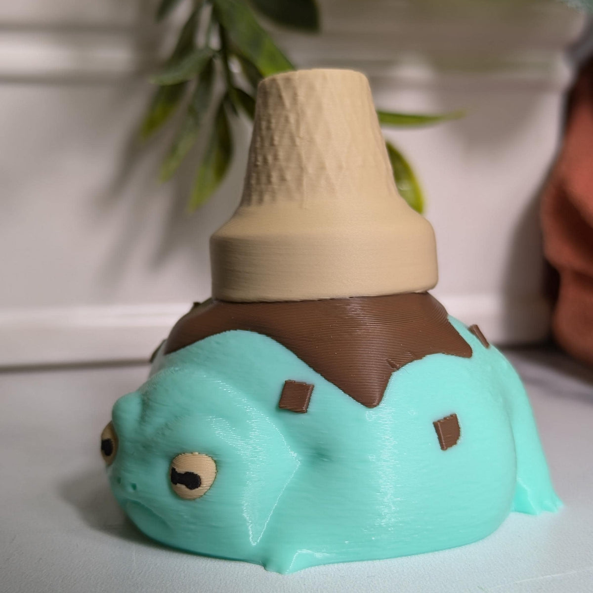 Side-front angle of the ice cream frog, caught mid-melt and mildly concerned about it.