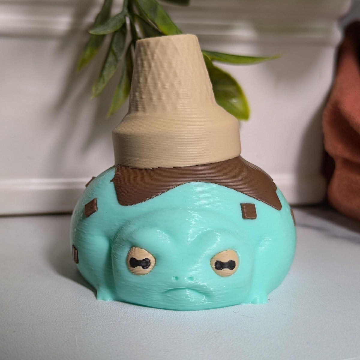 A front-facing mint chocolate chip frog with an upside-down cone hat and the energy of someone who knows they’re adorable.