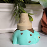 Side view of the mint chocolate chip ice cream frog, serving froggy gelato realness under a cone hat.