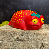 Angled shot of the strawberry frog sitting with a sleepy smirk and leafy crown