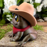 Alt text: Left side angle of Cowboy Frog figurine, showing the curve of the hat, the red bandana, and bright yellow eyes.