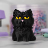 Black cat figurine with yellow eyes on a blurred background