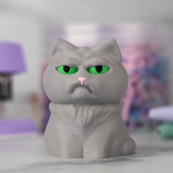 Gray cat figurine with green eyes and a pink nose on a blurred background