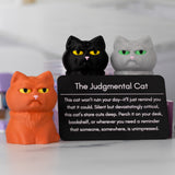 Three cat figurines with a card labeled 'The Judgmental Cat' on a white background
