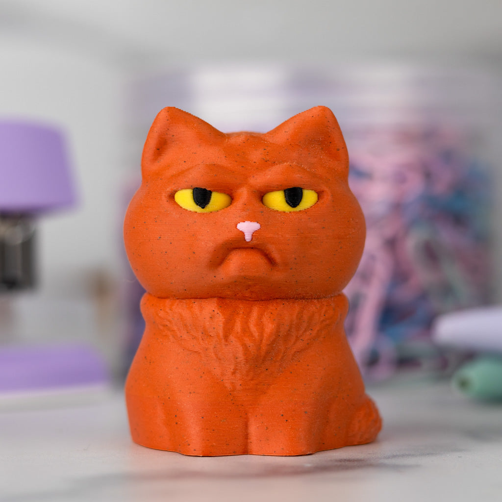 Orange cat figurine with a grumpy expression on a blurred background