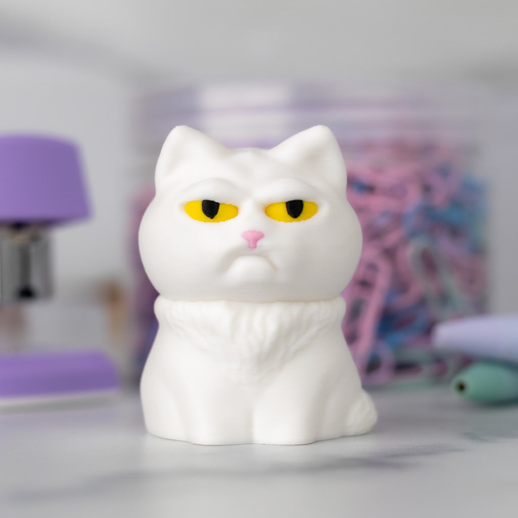 A very judgmental cat in white with yellow eyes is perched on a desk.