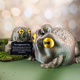 Three sizes of Judgmental Frog figurines with a metal description card on a blurred background.