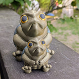 Front-facing view of both large and small Judgmental Turtle™ figurines together on a wood surface.